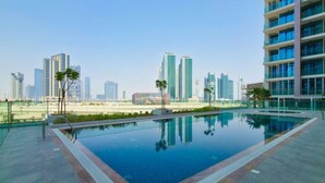 A rooftop pool with a city skyline view, surrounded by modern buildings. - Modern 1BR w/ Balcony | Maryah Vista Retreat (Abu Dhabi)