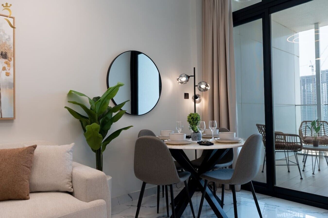 A modern dining area with a round table, chairs, and a large mirror.