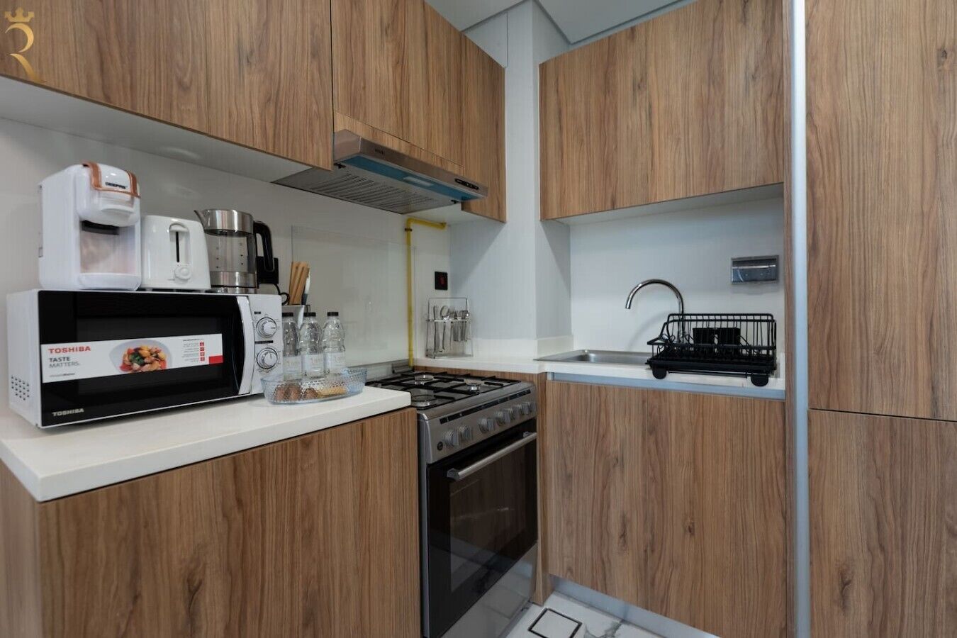A compact kitchen with wooden cabinets, a microwave, a stove, and a sink.