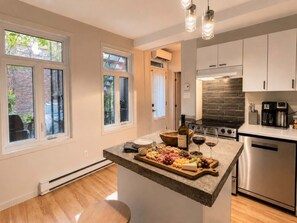 Una cocina moderna con una isla central, electrodomésticos de acero inoxidable y ventanas amplias.