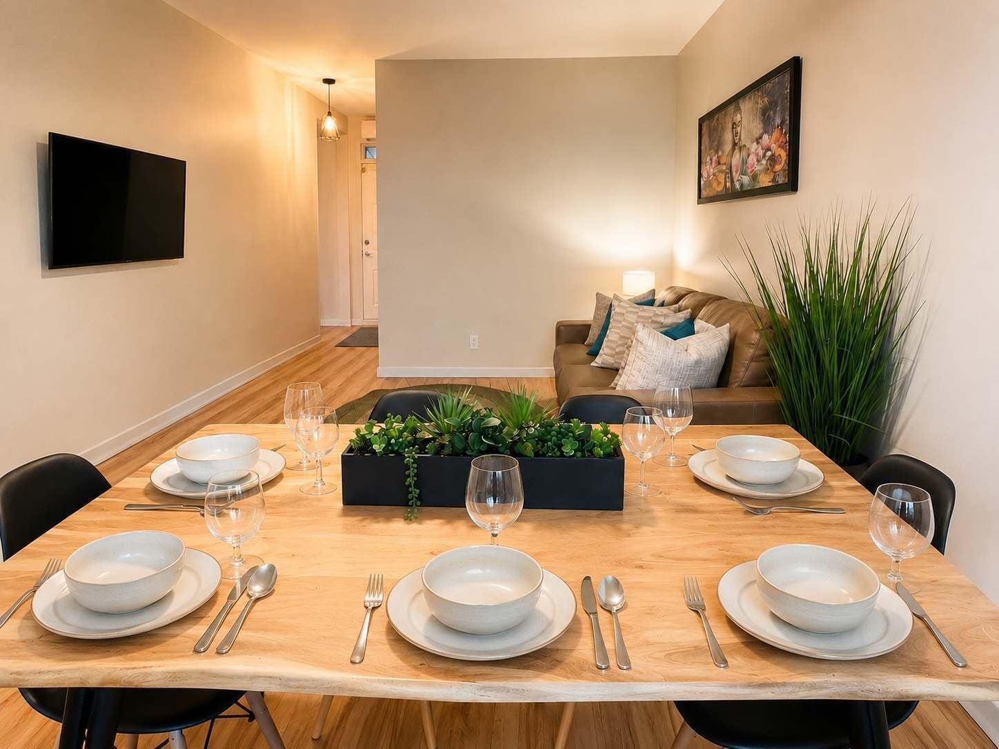 A dining area with a wooden table set for four, surrounded by chairs.