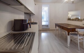 Een keuken met een inbouwoven, een eettafel met stoelen en een uitzicht door een raam.