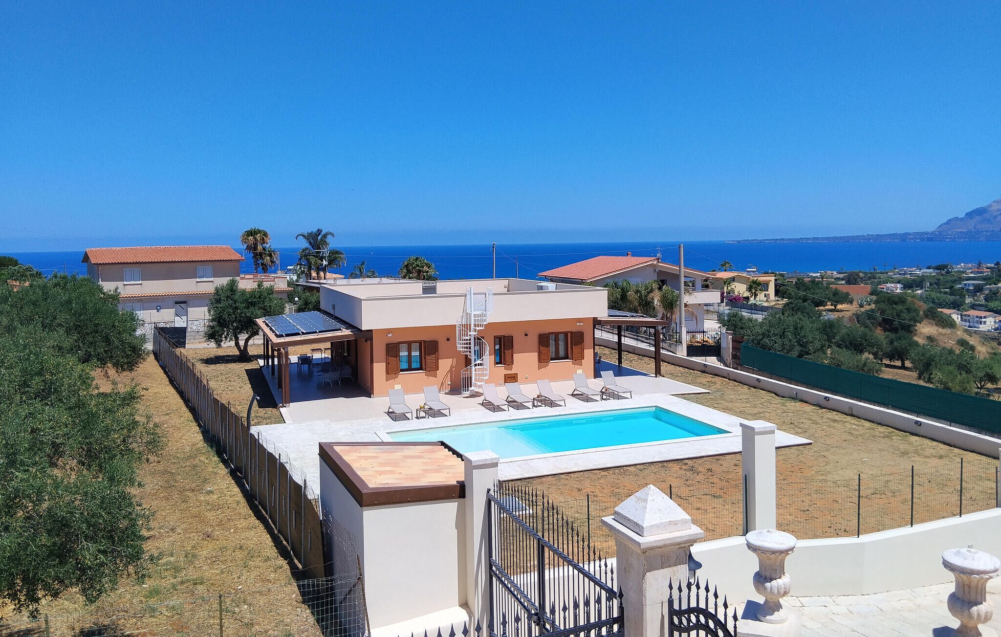 A modern villa with a swimming pool, solar panels, and a view of the sea.