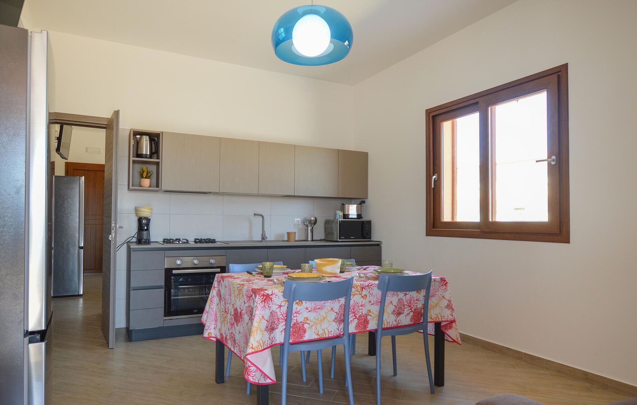 Cocina compacta con comedor, ventana y lámpara en el techo.