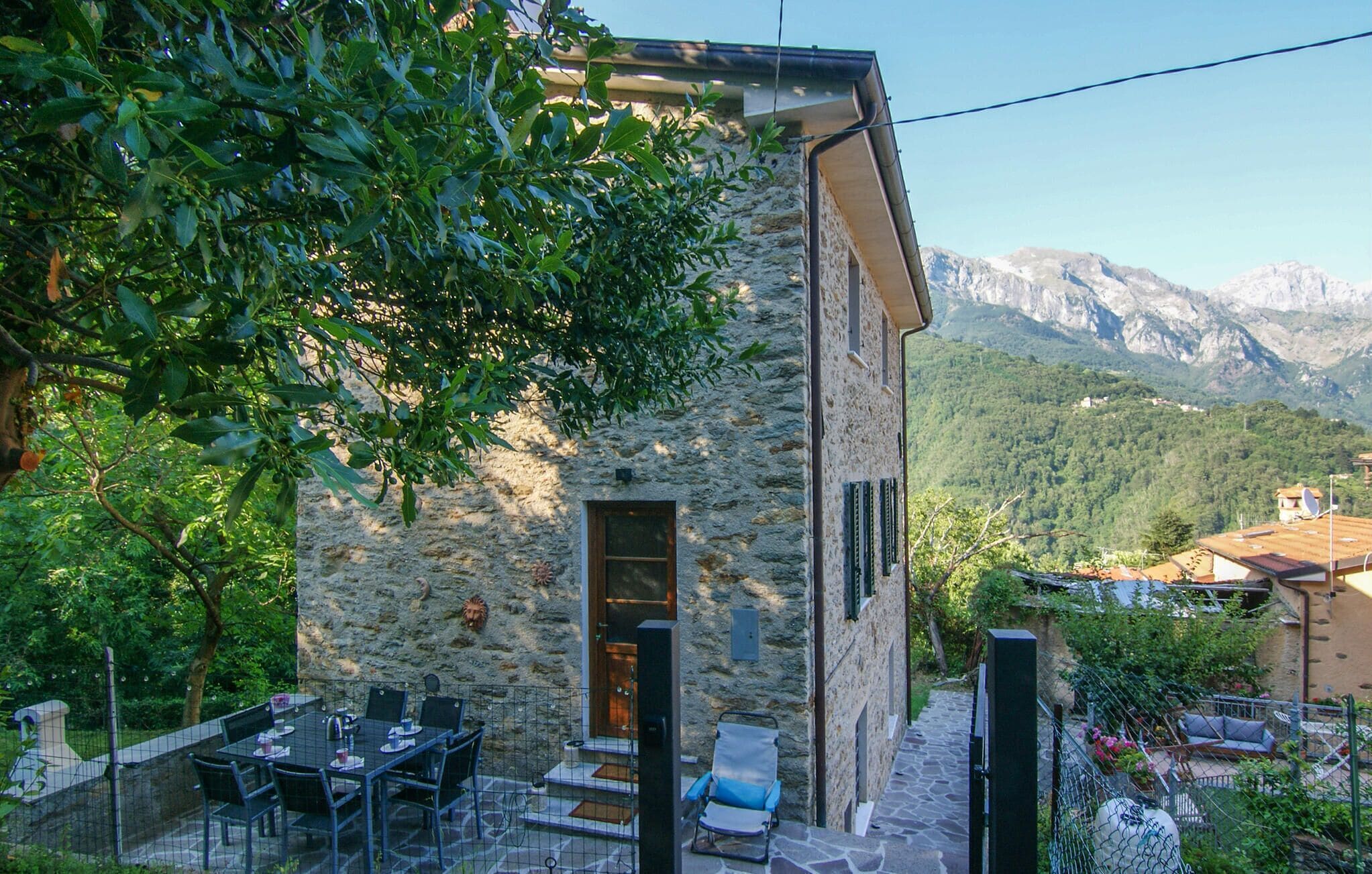 A stone building with a dining area, outdoor seating, and a mountain view.