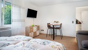 Ett sovrum med en säng, ett skrivbord med en stol, en tv och utsikt över omgivningen.