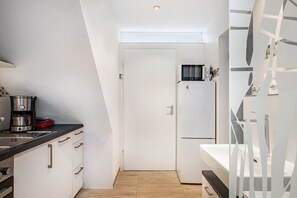 Una cocina compacta con cafetera, refrigerador y microondas.