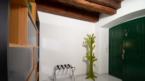 A room with a green door, a wooden shelf, a metal bench, and a green abstract sculpture.
