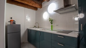 A kitchen with a refrigerator, sink, cabinets, and a window.