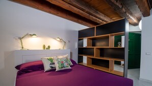 A bedroom with a bed, pillows, a nightstand, a lamp, and a built-in shelving unit.