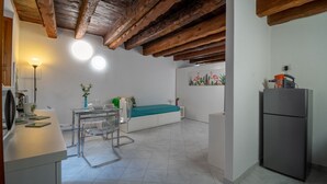 A compact kitchen with a dining area, a refrigerator, and a wall-mounted artwork.