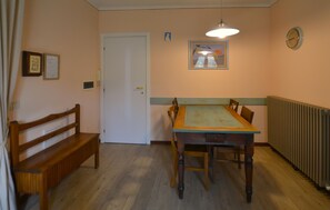 Uma sala de jantar com uma mesa e cadeiras de madeira, um banco, uma porta e um radiador.