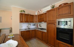 Uma cozinha com armários de madeira, micro-ondas de aço inoxidável e fogão a gás.