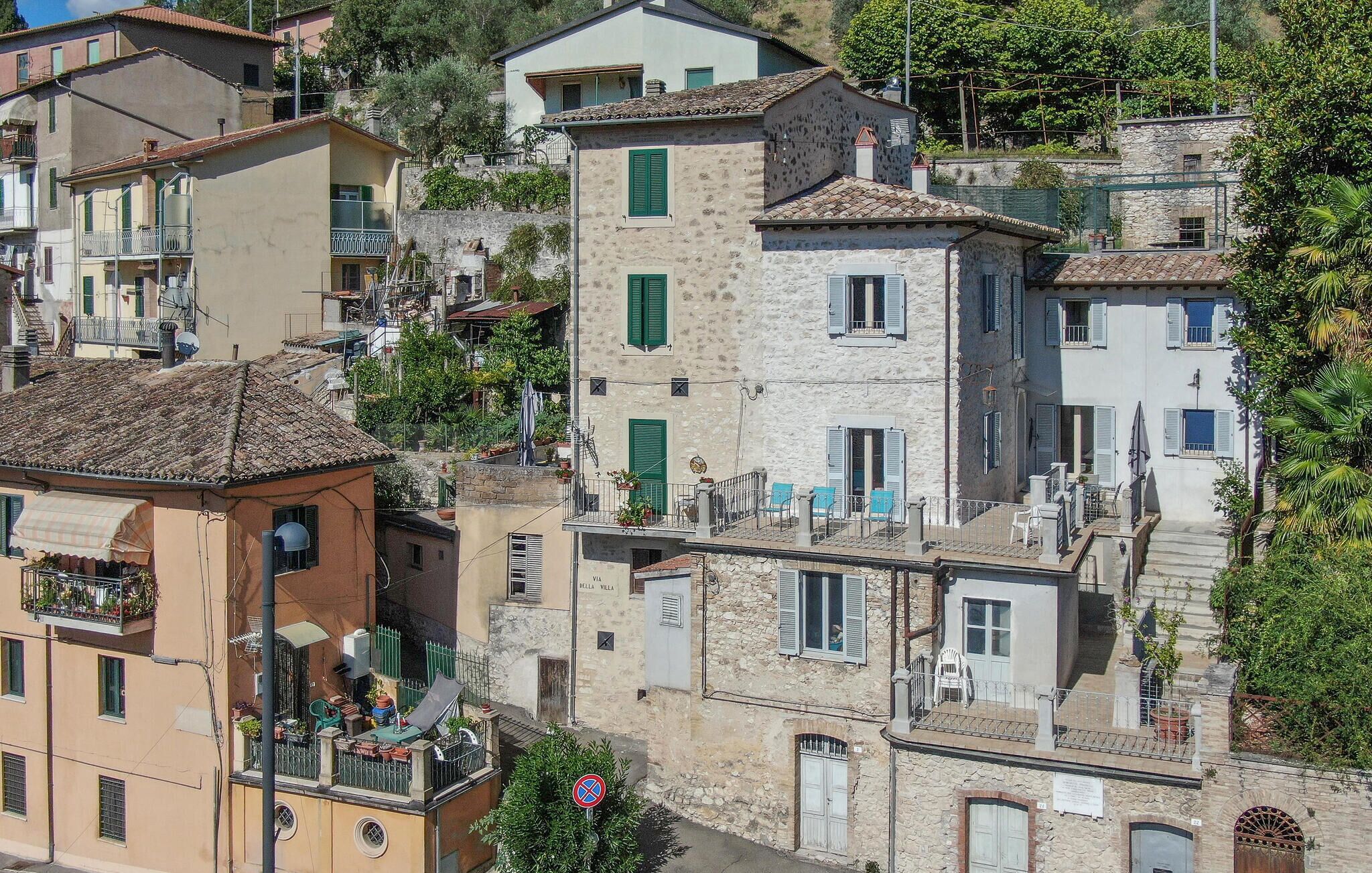 Un immeuble à plusieurs étages doté de balcons, une enseigne indiquant « VIA Cella Villa » et un panneau interdisant le stationnement.
