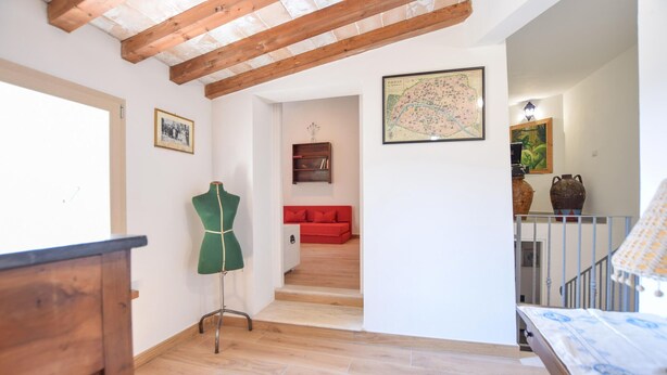 Um quarto com teto de madeira, um manequim verde, um sofá vermelho, um mapa e uma escada.