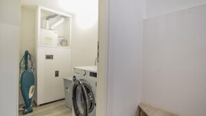 Uma lavanderia com máquina de lavar, secadora e aquecedor de água.