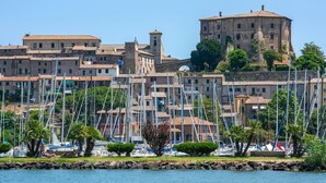 Uma cidade costeira com edifícios históricos, uma torre imponente e uma marina com muitos barcos.