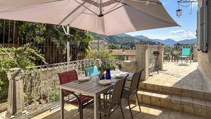 Uma área de refeições ao ar livre com uma mesa, cadeiras e um guarda-sol.
