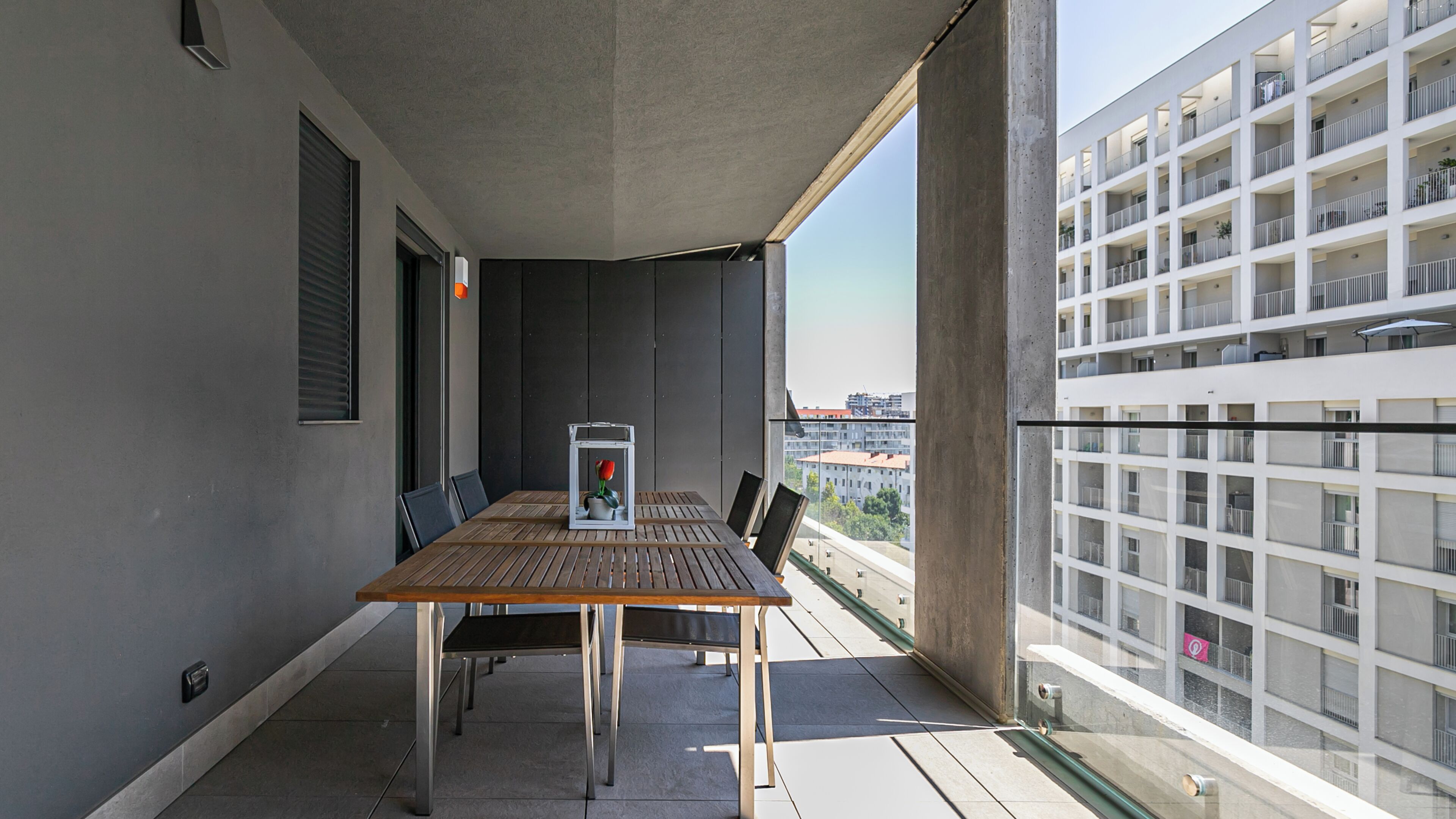 Ein Balkon mit Tisch und Stühlen, einer Topfpflanze und Blick auf ein Gebäude.