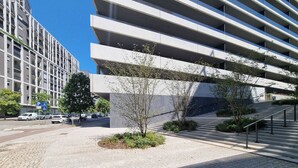Un edificio moderno con varios pisos, una zona de estacionamiento y una escalera que conduce a un nivel superior.
