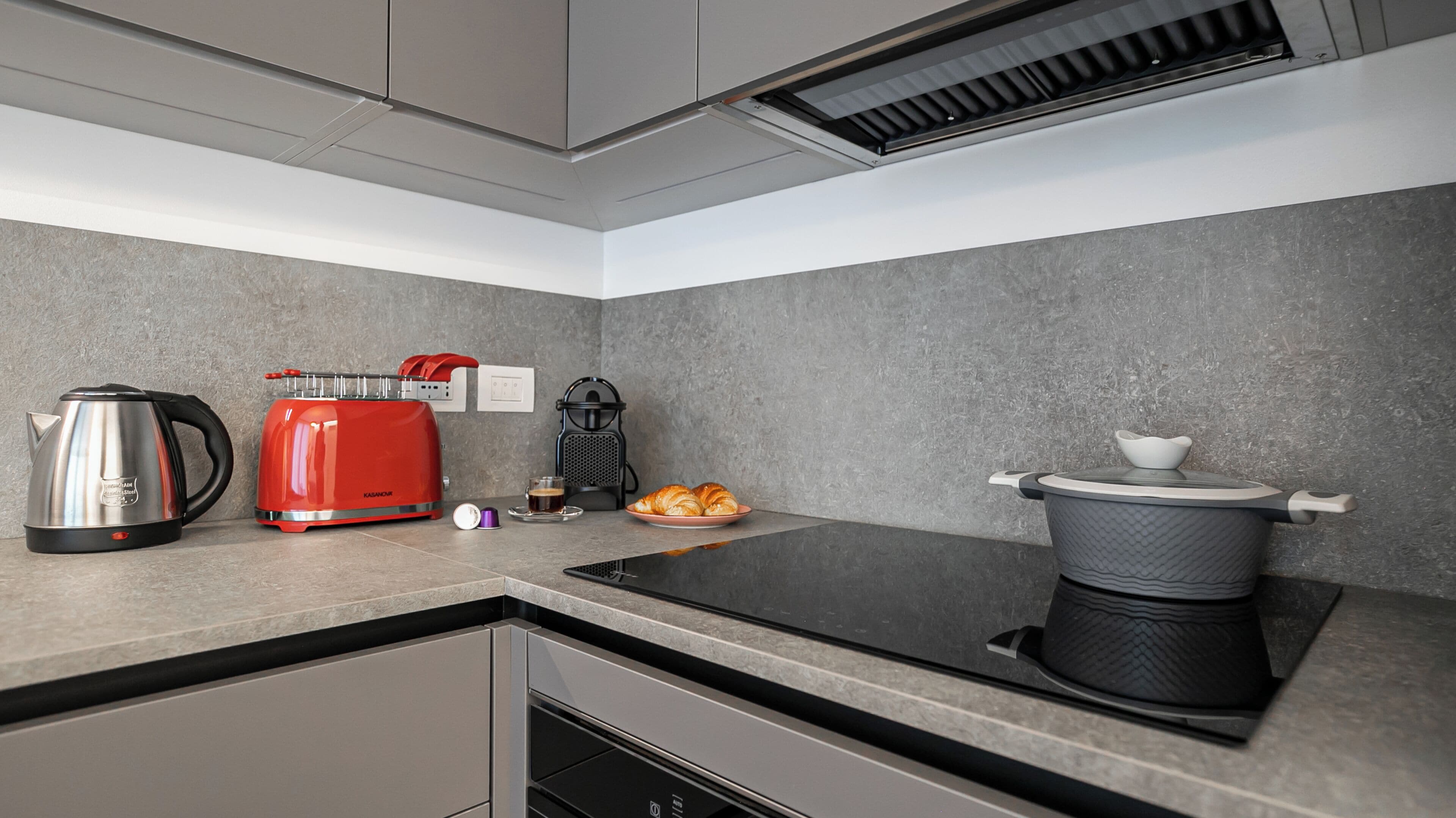 Una cocina moderna con estufa integrada, hervidor, tostadora y cafetera.