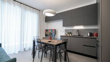 Une cuisine moderne avec des meubles gris, un évier noir et un grille-pain rouge.