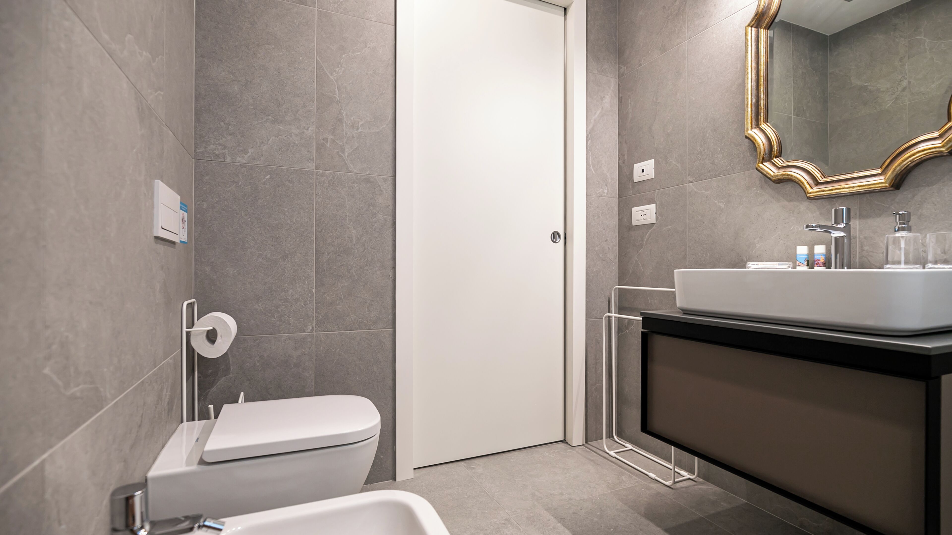 Ein modernes Badezimmer mit Toilette, Waschbecken und Spiegel.