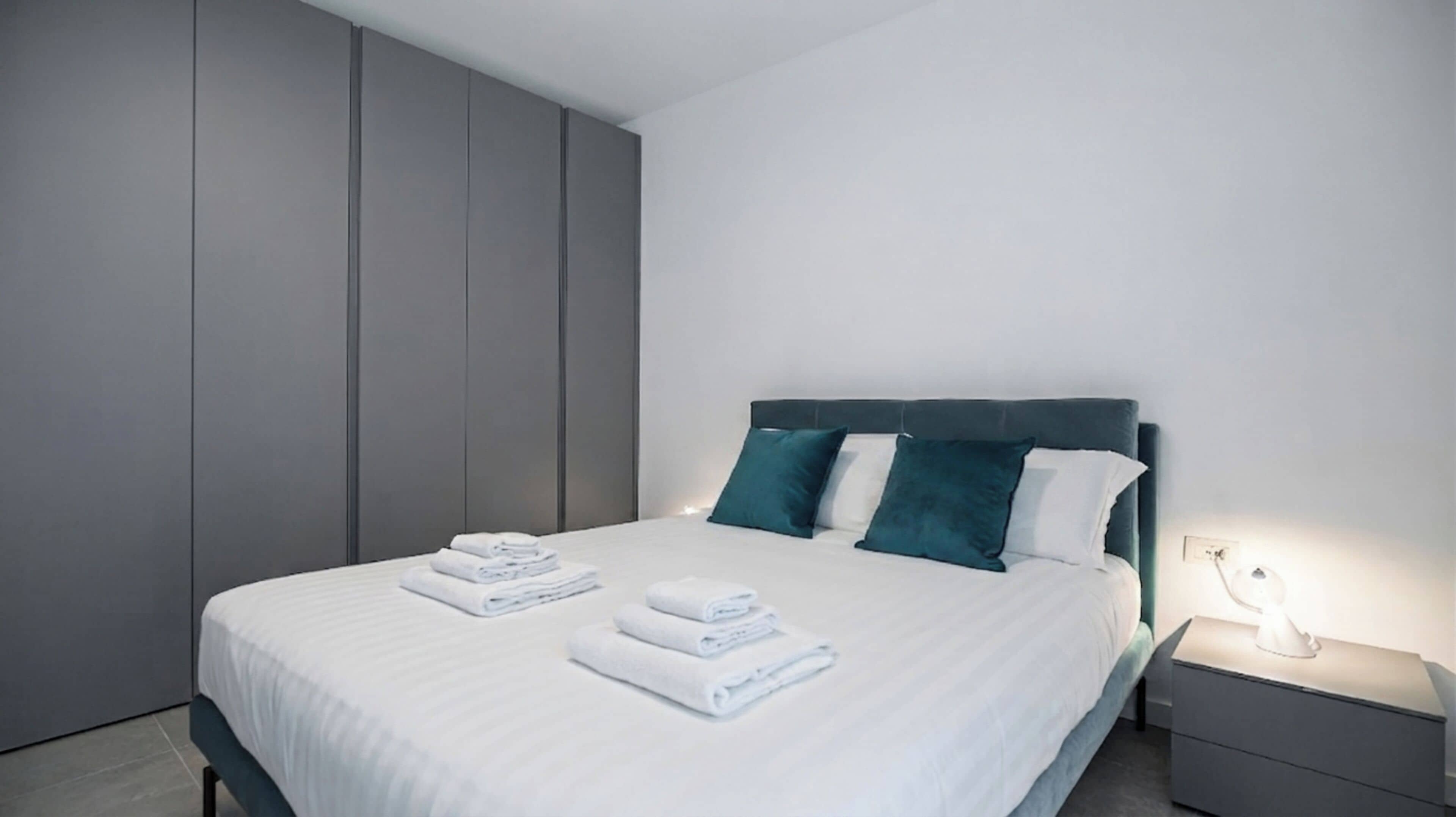 Un dormitorio moderno con una cama, almohadas y una mesita de noche.