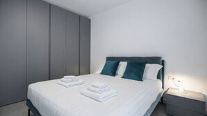 Un dormitorio moderno con una cama, almohadas y una mesita de noche.