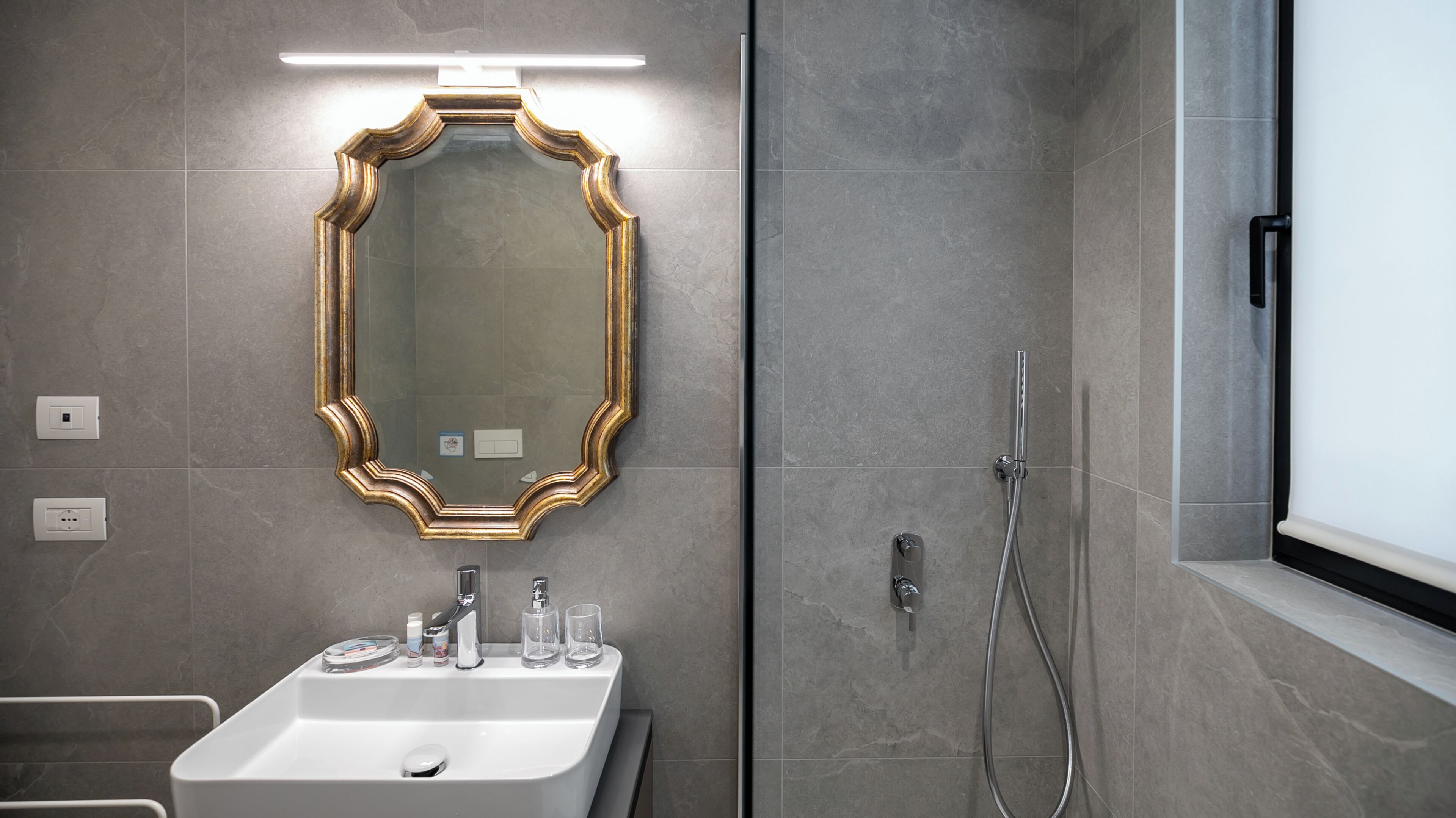 Un bagno moderno con uno specchio grande, un lavandino e una doccia.