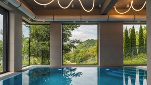 Una piscina interior con vistas a una ladera boscosa.