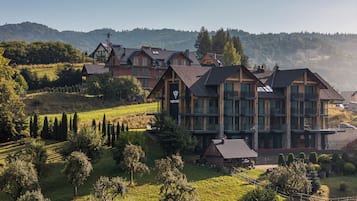 A large, multi-story building with a prominent logo, surrounded by lush greenery and hills.
