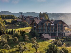 A large, multi-story building with a prominent logo, surrounded by lush greenery and hills.
