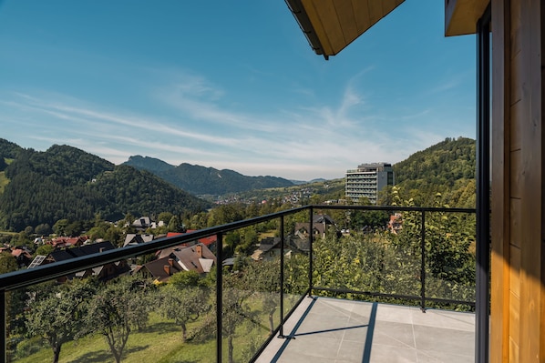 Un balcón con vistas despejadas a un paisaje montañoso, un edificio moderno y una zona residencial.