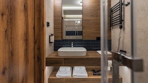 Un baño moderno con tocador de madera, un espejo grande, un perchero y un dispensador de toallas.