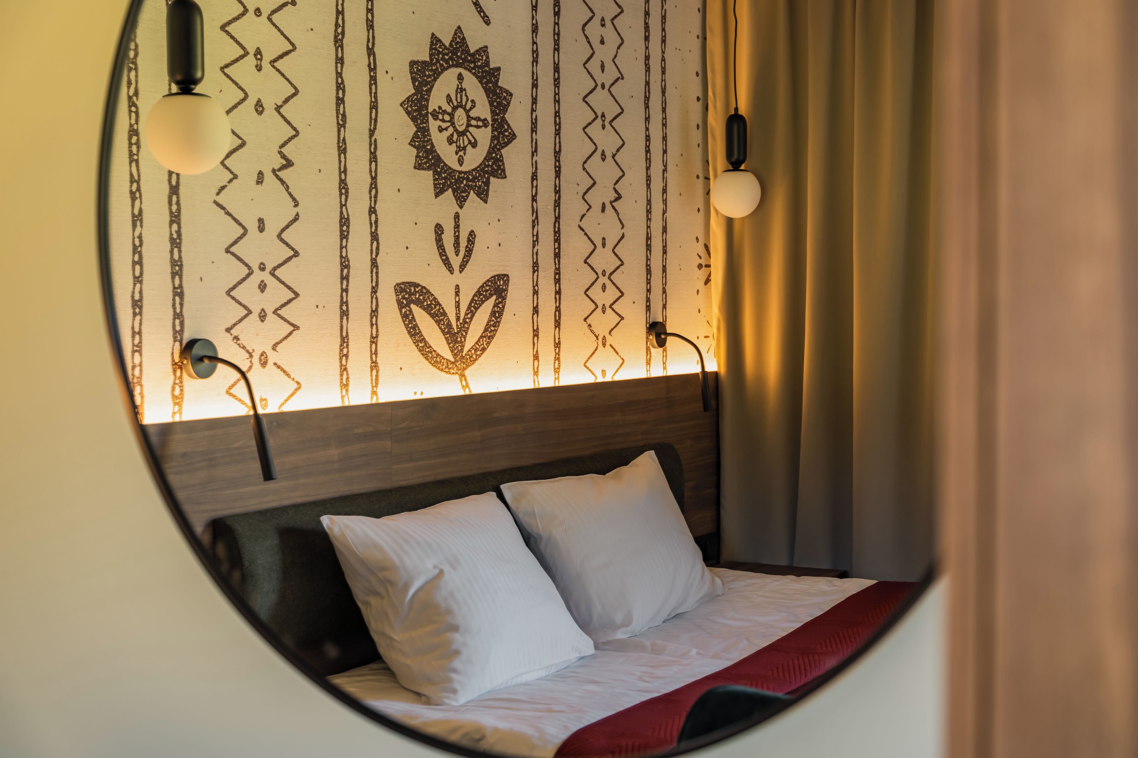 Ein Rundblick auf ein Hotelzimmer mit Bett, Kopfteil und einer Wand mit Zierverzierungen.