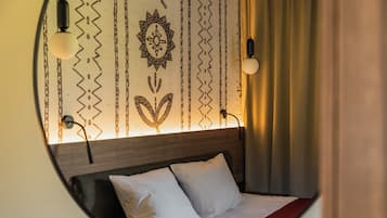 Ein Rundblick auf ein Hotelzimmer mit Bett, Kopfteil und einer Wand mit Zierverzierungen.