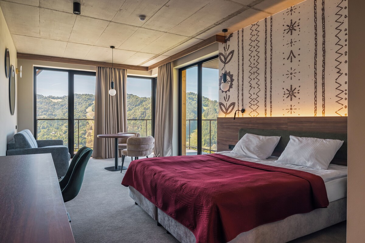 Una habitación de hotel con una cama grande, un escritorio, una silla y vistas al exterior.