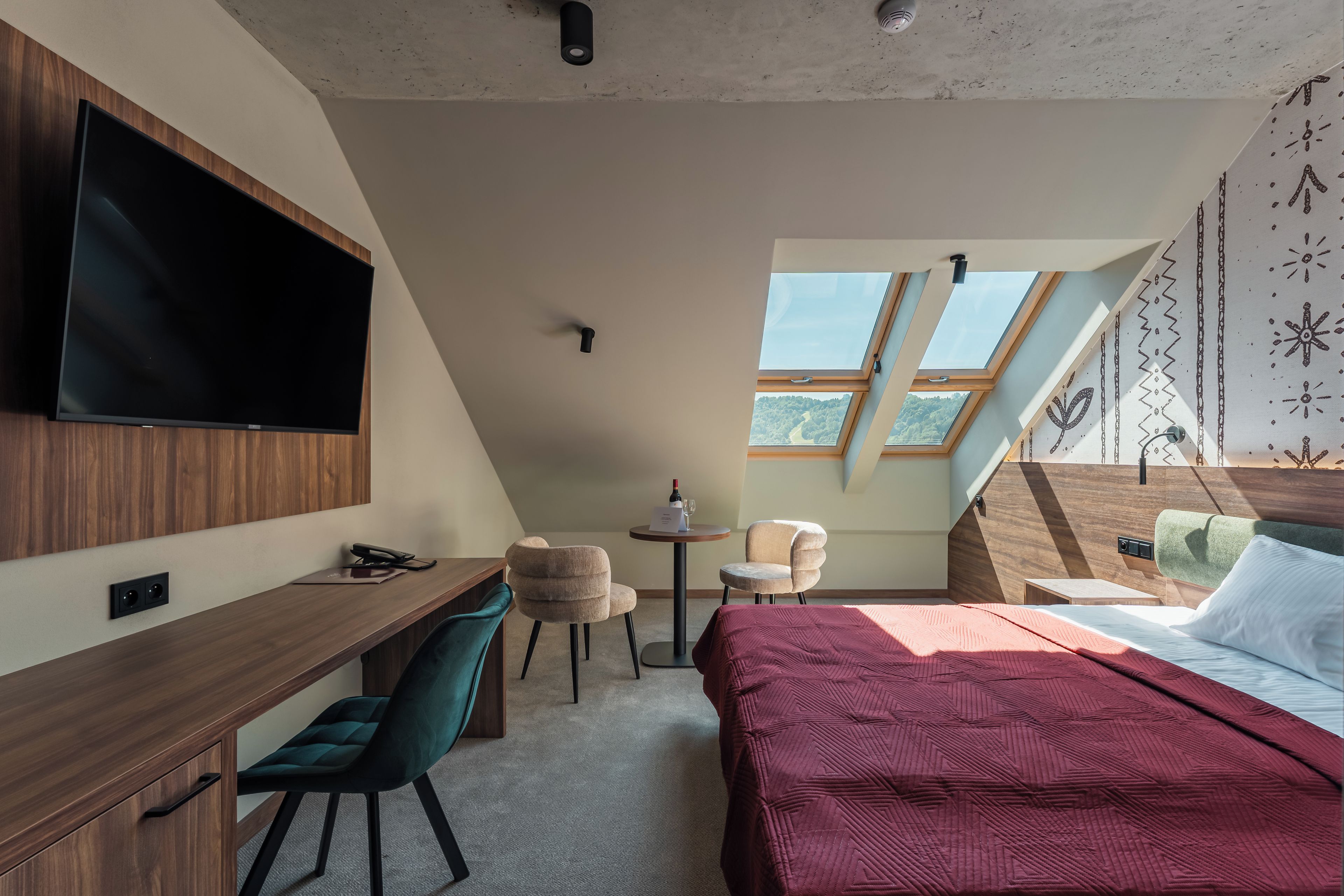 Een knus slaapkamer met een bed, een bureau, een stoel, een televisie en dakramen.