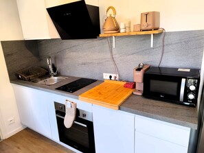 Eine moderne Küche mit Spüle, Herd, Backofen, Mikrowelle und Schneidebrett.
