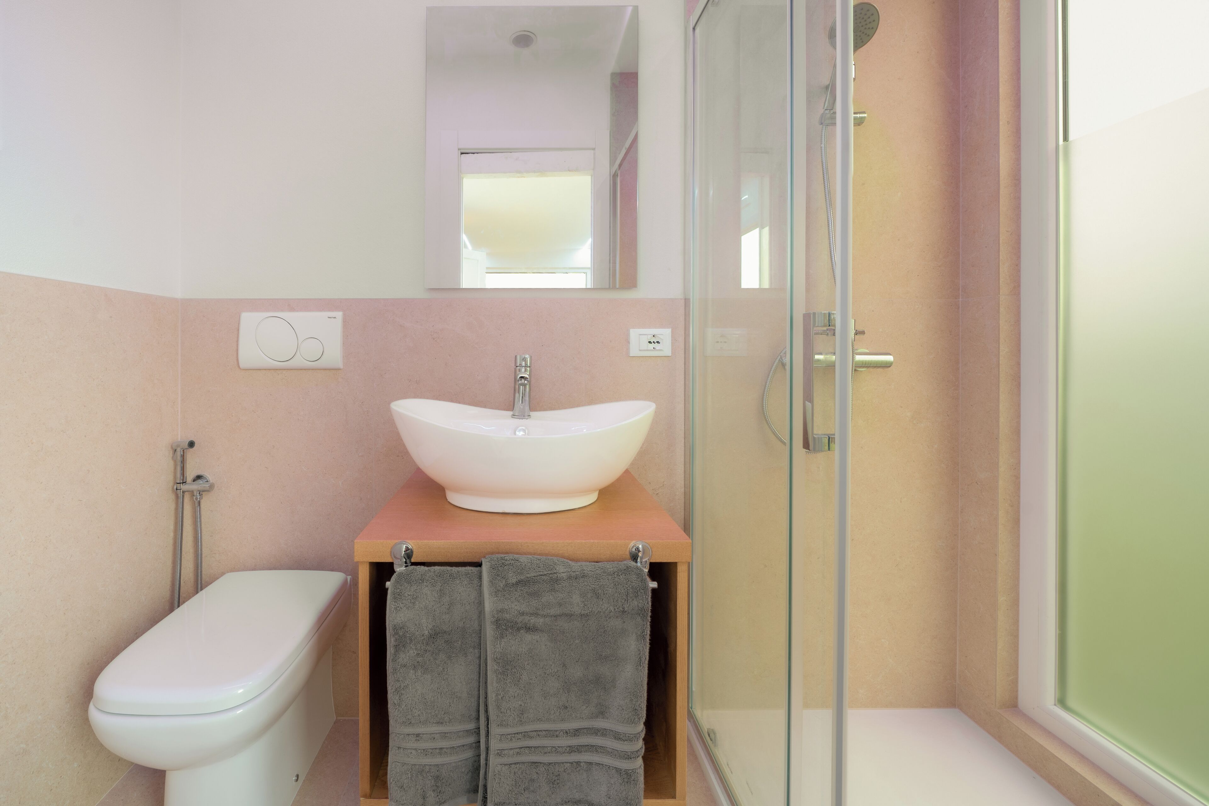 Een badkamer met toilet, een wastafel met waskom en een douchehoek.