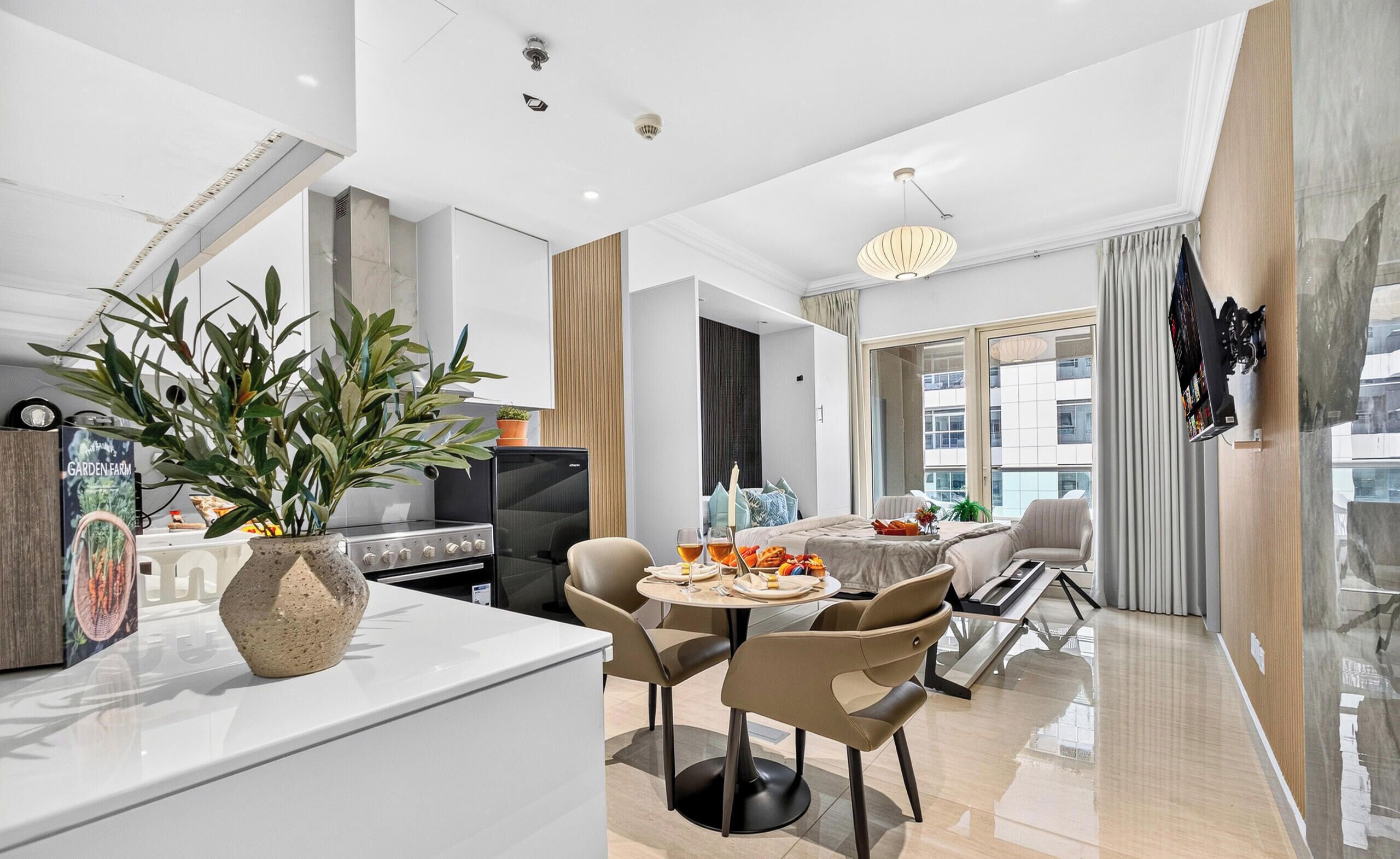A modern kitchen with a stove, dining table, and chairs. There is a potted plant on the counter.