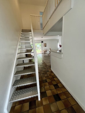 Eine Treppe mit Schachbrettmuster führt zu einer Zwischenebene im zweiten Stock.