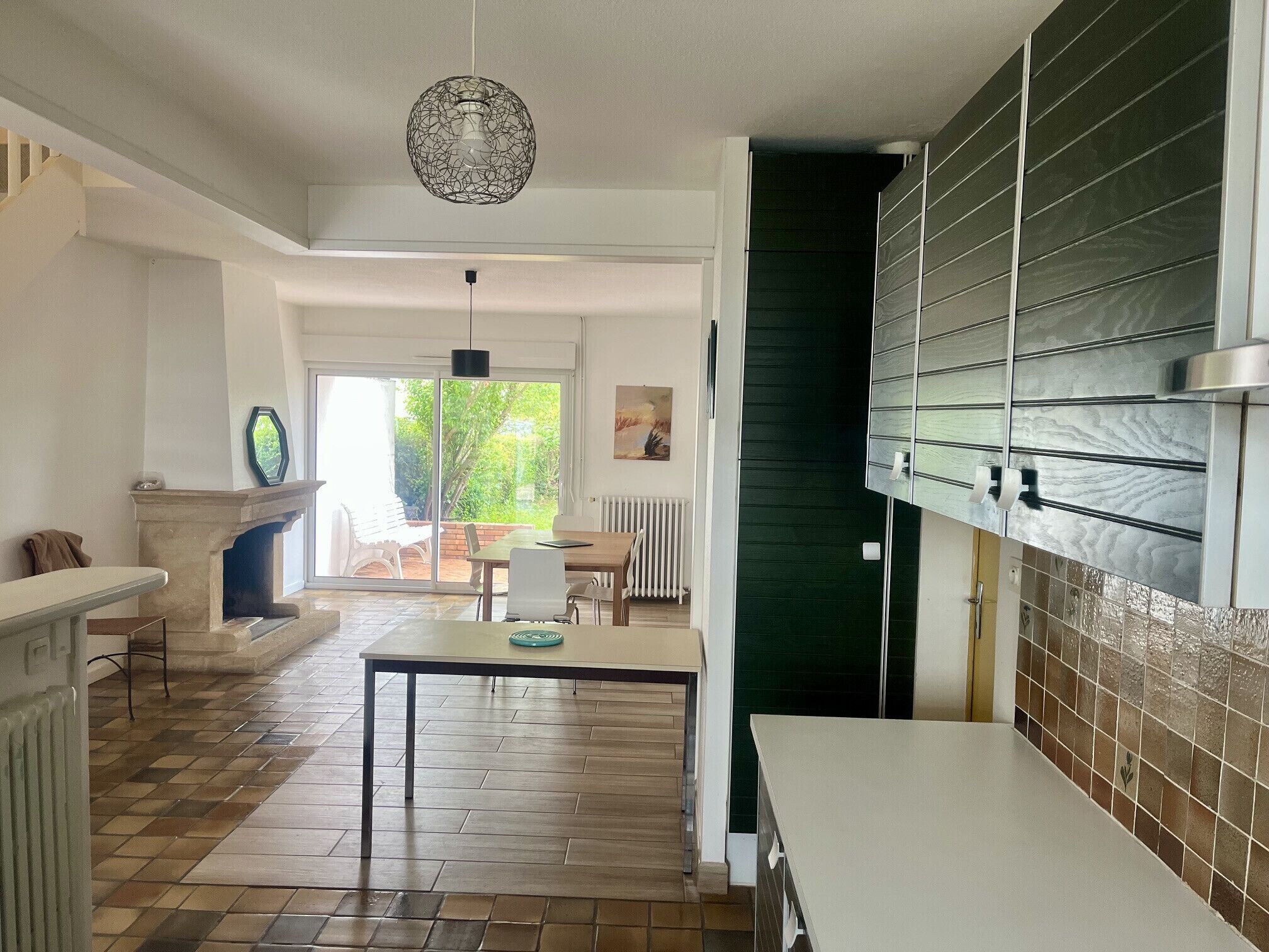 Un'ampia cucina con zona pranzo, camino e vista sul verde.