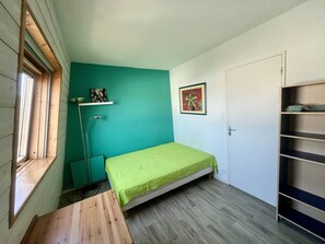 A small room with a bed, a desk, a floor lamp, and a door. - Maison pour 8 proche centre ville (La Rochelle)