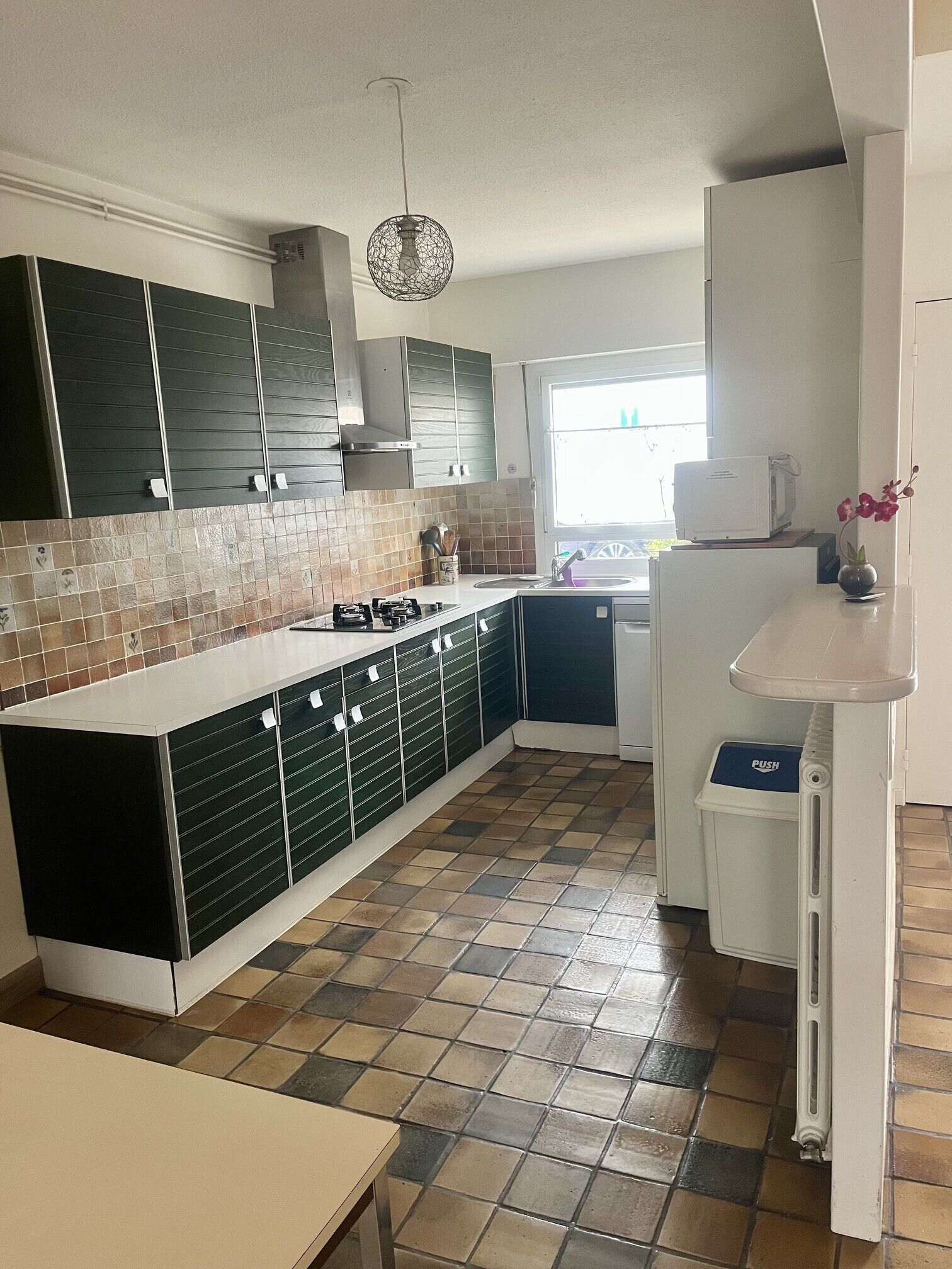 Una cucina moderna con isola centrale, pensili integrati, piano cottura a gas e lampadario.
