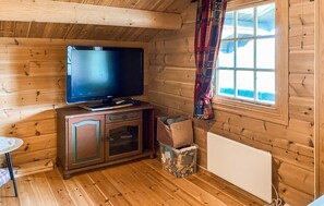 A wooden cabin interior with a television on a cabinet, a small table, and a window with curtains. - Stunning home in Bjorli with WiFi (Bjorli)