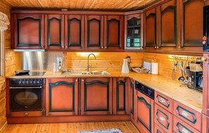 A kitchen with wooden cabinets, a stainless steel range hood, a sink, and a dishwasher. - Stunning home in Bjorli with WiFi (Bjorli)