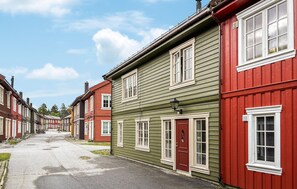 A row of traditional wooden houses with distinct red and green facades, aligned along a narrow street. - Stunning home in Bjorli with WiFi (Bjorli)