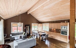 Ein geräumiger Wohnbereich im Loft-Stil mit hohen Decken, einem Esstisch und einer Küchenzeile mit Holzschränken und Geräten.